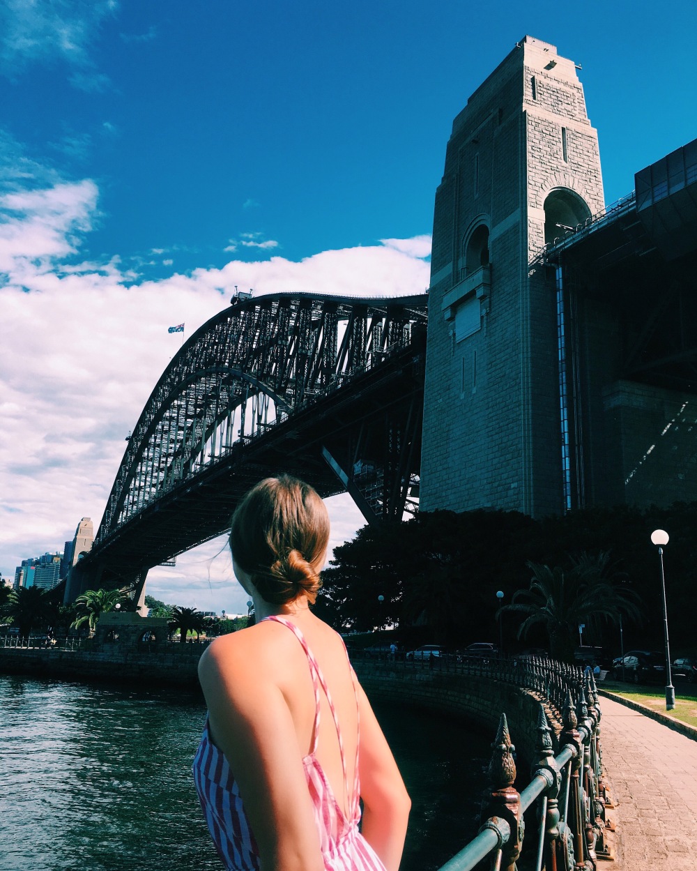 Young woman looks up at the huge Sydney Harbour Bridge