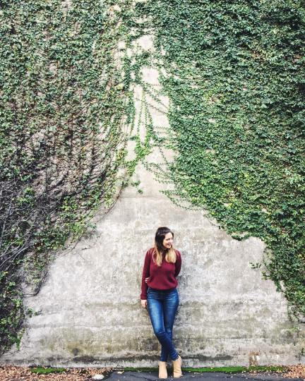 Young woman stands against a vine covered wall in Sydney, Australia